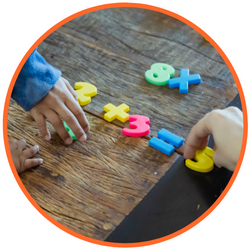 Toddler playing with colored numbers and math symbols.